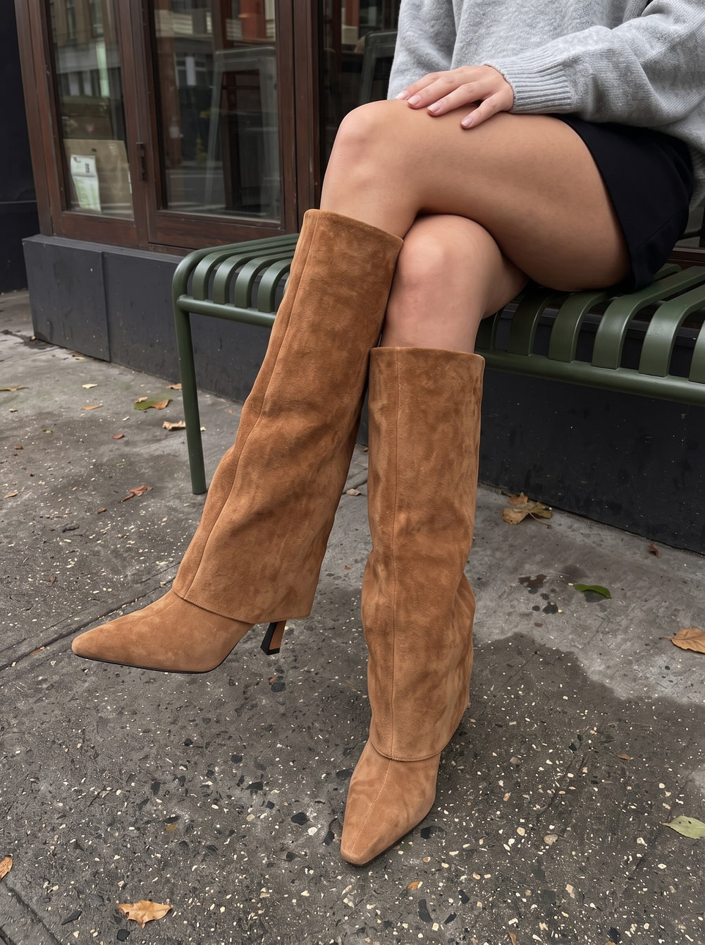 Ila brown suede knee-high boots with fold-over shaft and pointed toe, worn outside a London cafe