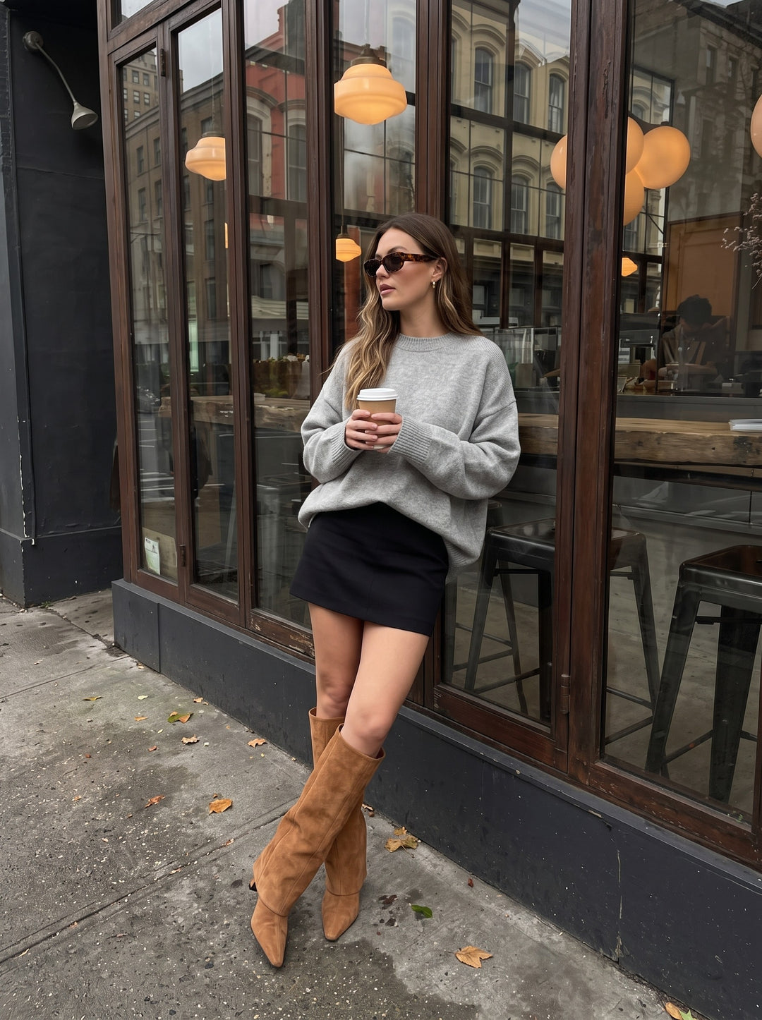 Ila brown suede knee-high boots with fold-over shaft and pointed toe, worn outside a London cafe